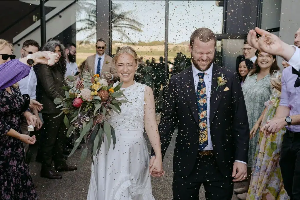 Couple walking through a shower of petals outside the venue