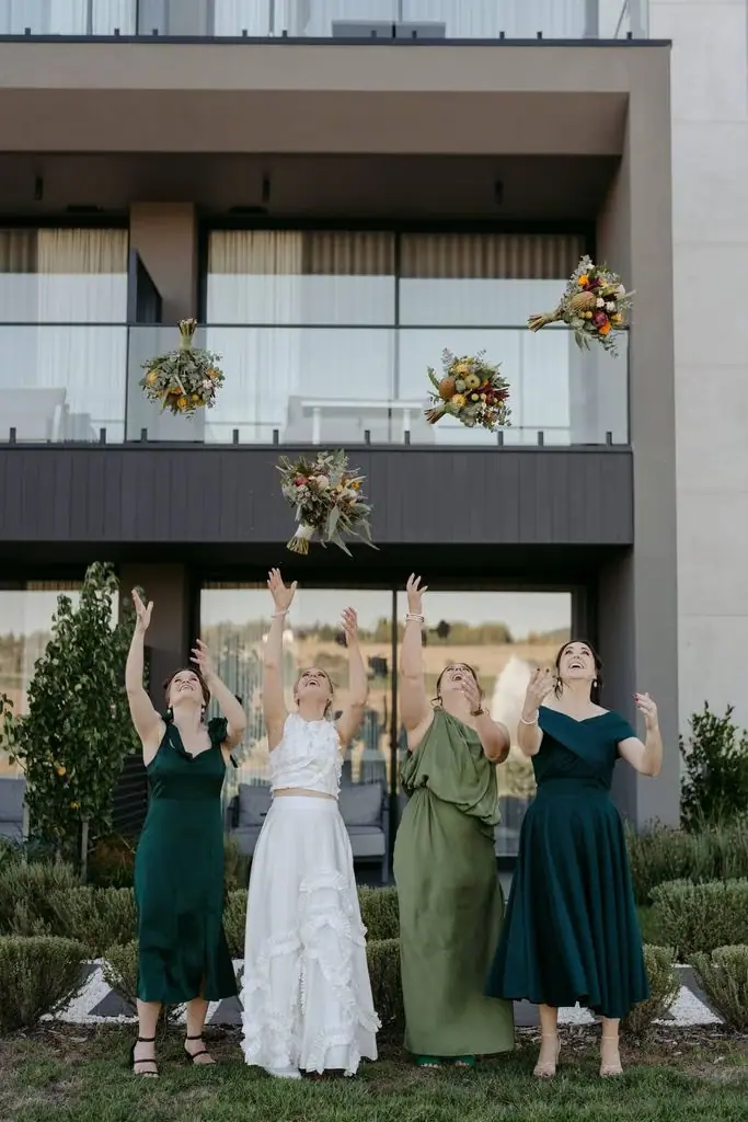 Bride and bridesmaids raising their arms outside the venue