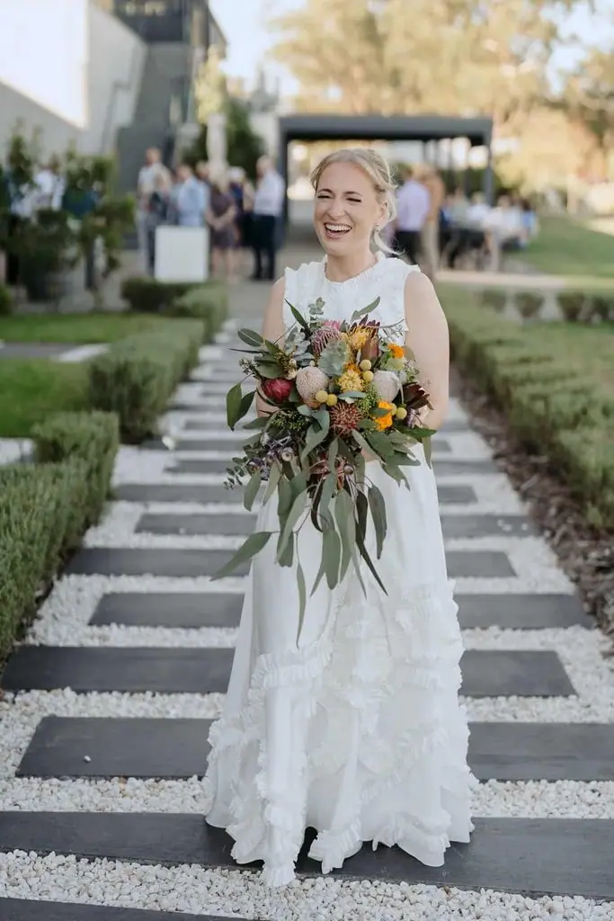 Bride smiling with her bouquet on the venue steps