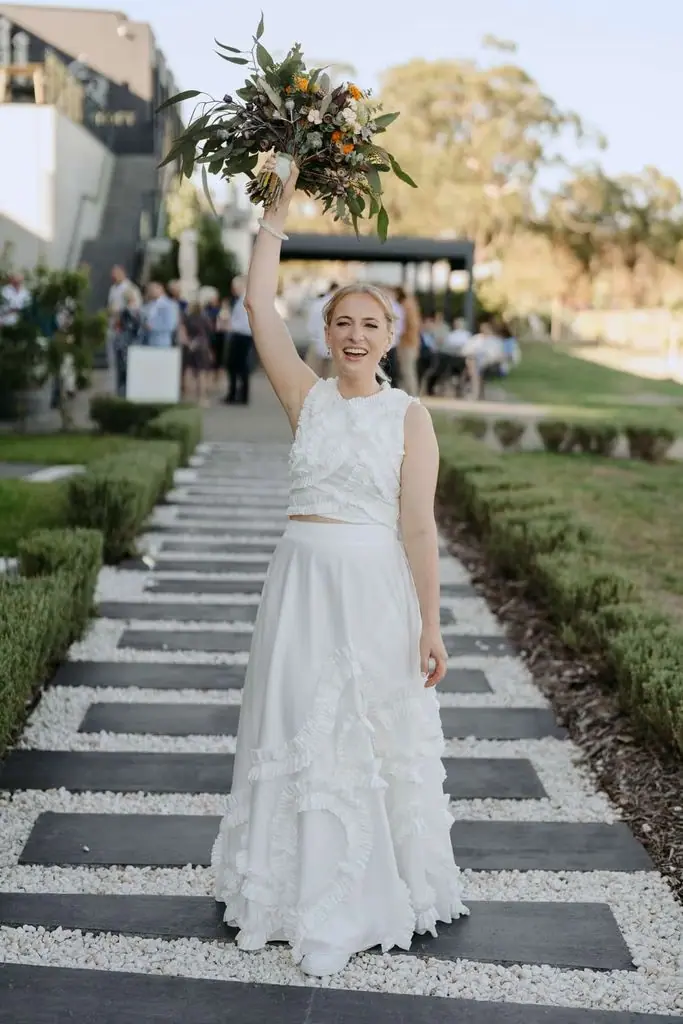 Bride lifting her bouquet above her head on the steps