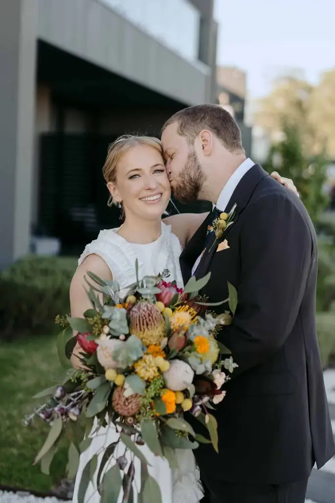 Groom kissing the bride's head outside the venue
