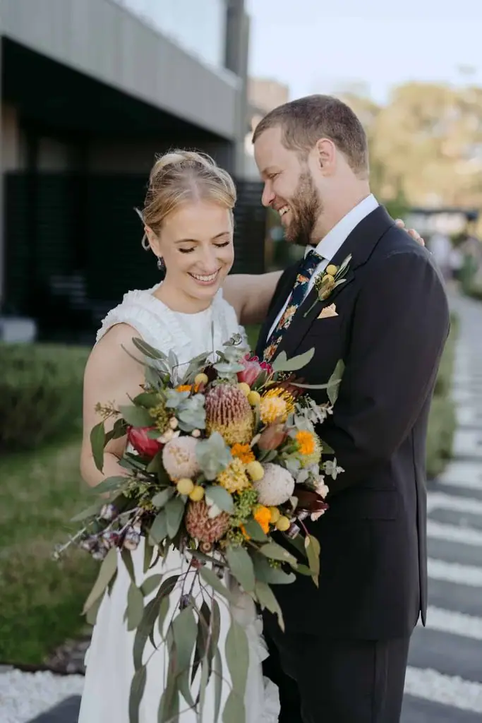 Couple looking down at the bride's bouquet