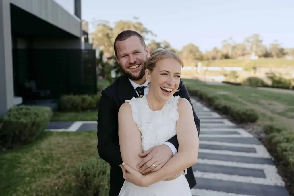 Groom embracing the smiling bride from behind