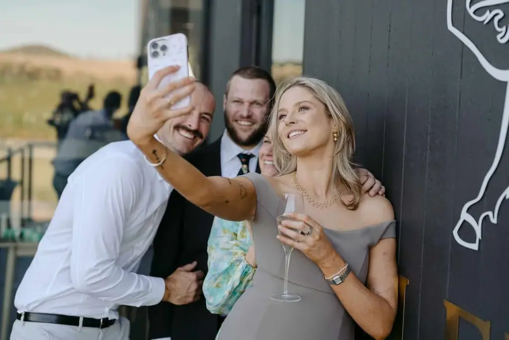 Three guests smiling for a phone selfie