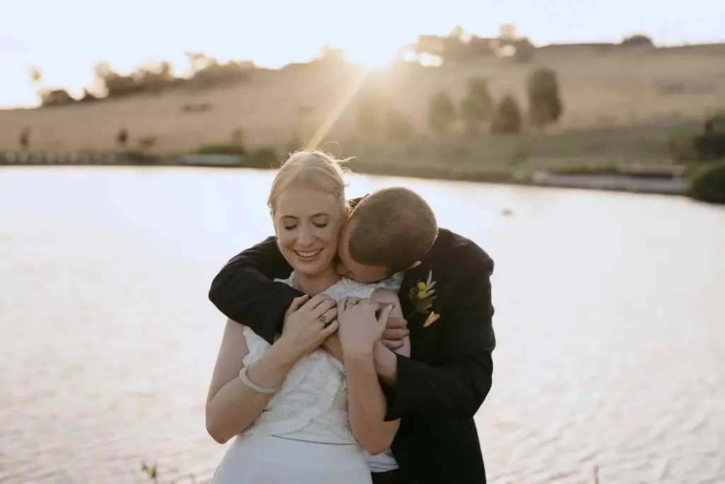 Couple laughing as the groom leans towards the bride's shoulder