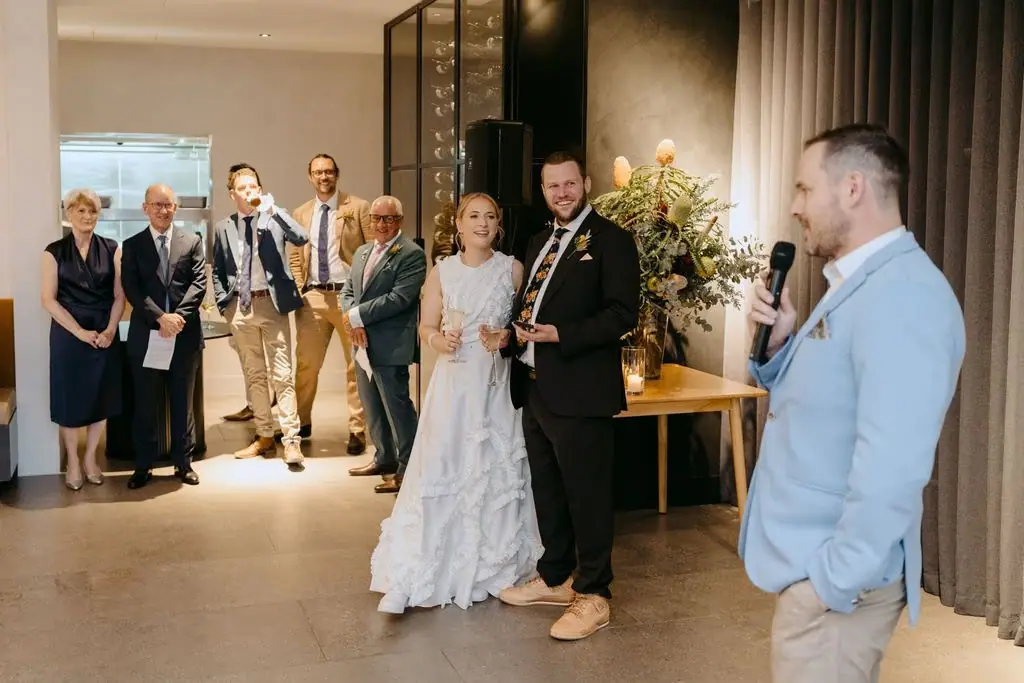 Newlyweds entering the reception beside the master of ceremonies