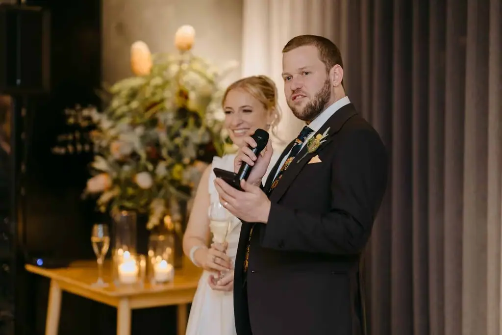 Groom holding a microphone with the bride beside him