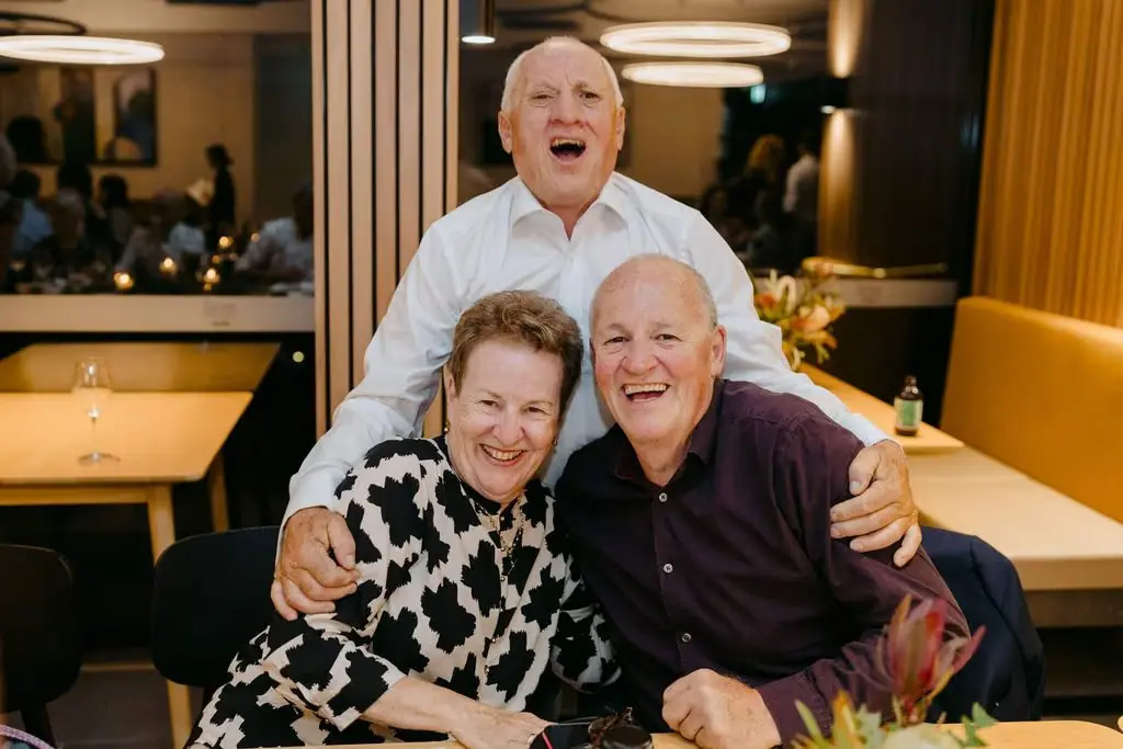 Three guests laughing and posing together at the reception