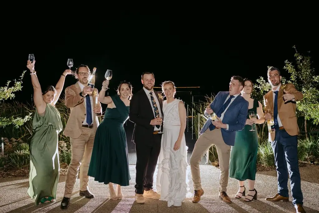 Wedding party raising bottles outside after dark