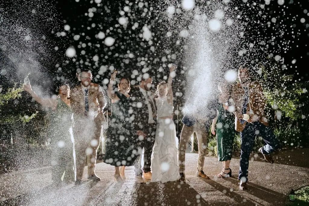 Wedding party spraying sparkling wine outside at night