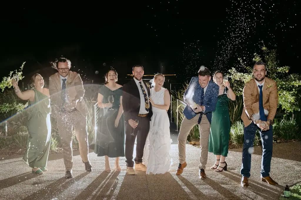 Wedding party cheering amid a spray of sparkling wine