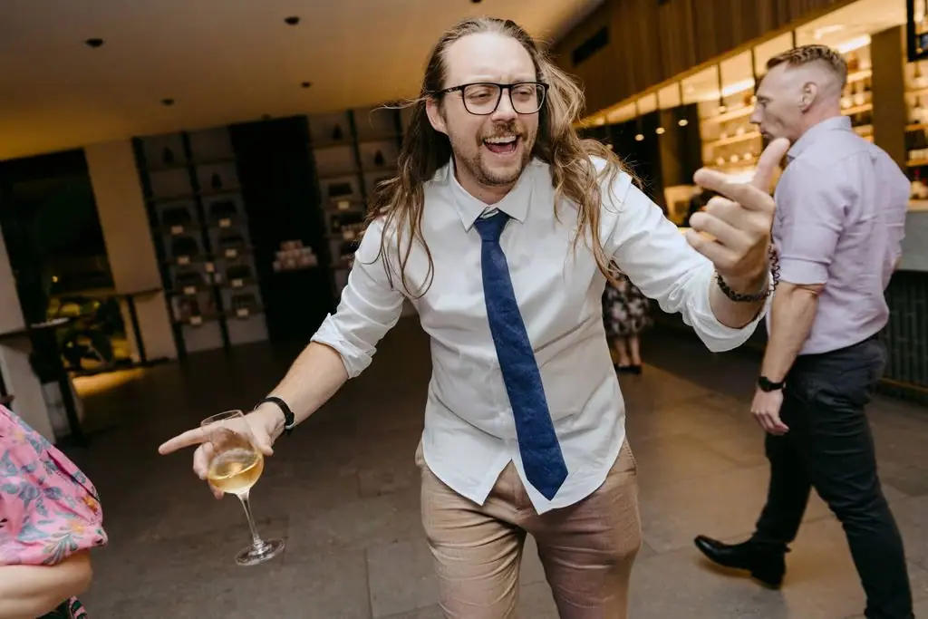 Guest with glasses dancing while holding a drink