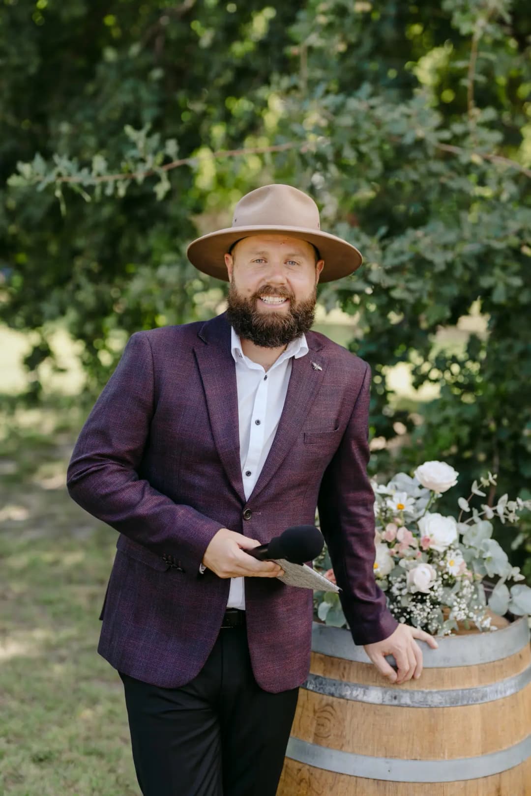 Man wearing a broad-brimmed hat beside a barrel of wedding flowers.