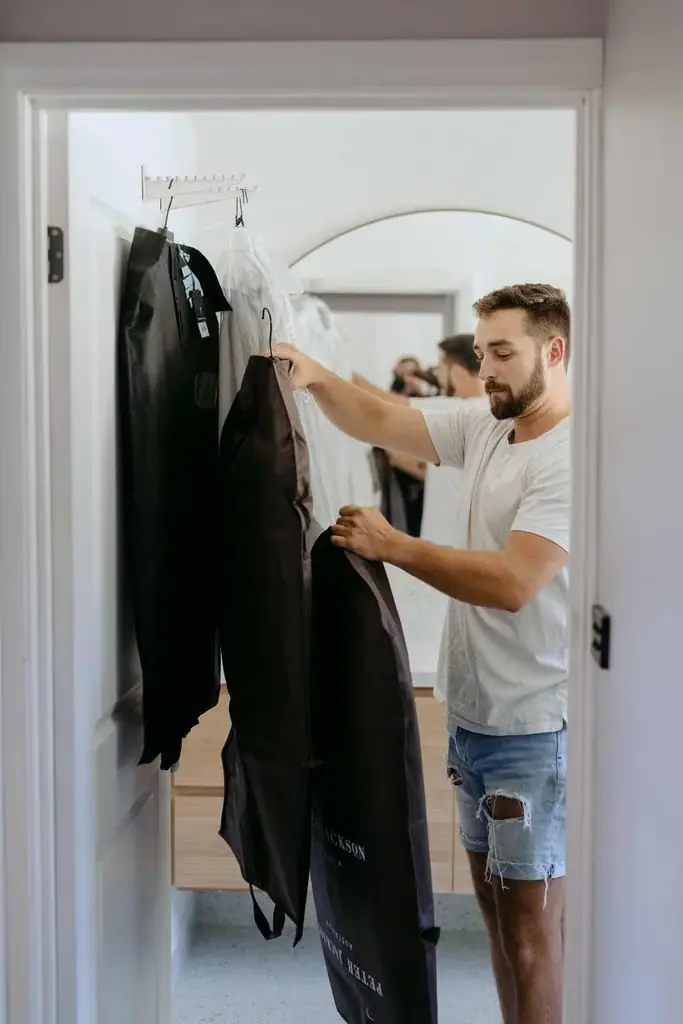 Groom selecting his wedding suit from a wardrobe