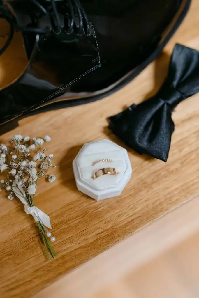 Bow tie, buttonhole flowers and a ring box on a timber table