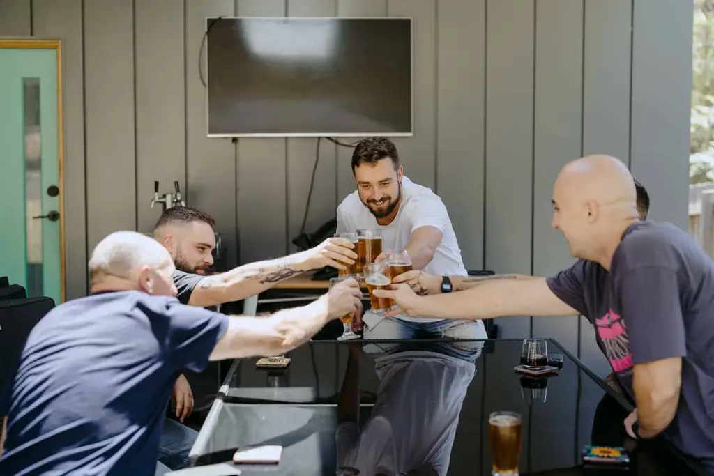 Men clinking drinks around a table while getting ready