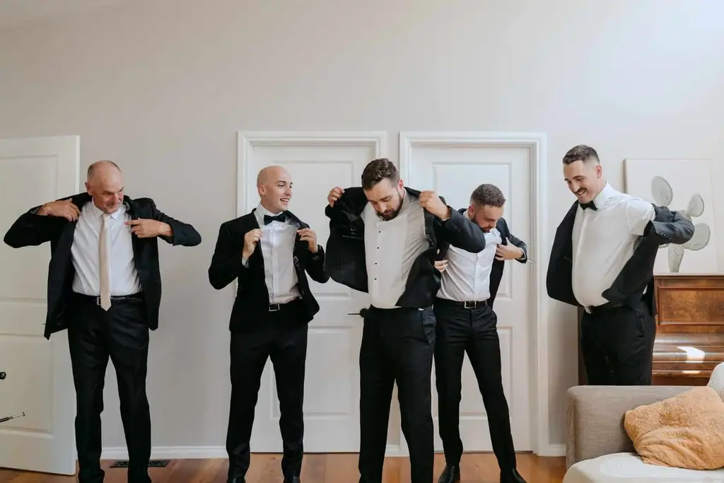 Groom and groomsmen adjusting their clothes while getting ready