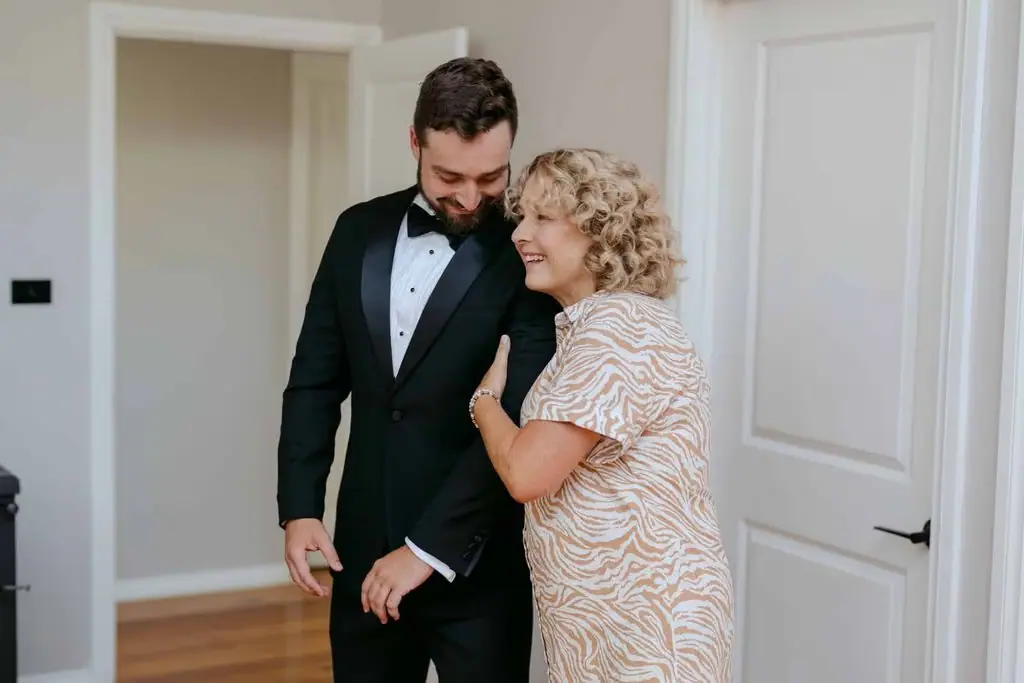 Groom standing beside an older guest indoors
