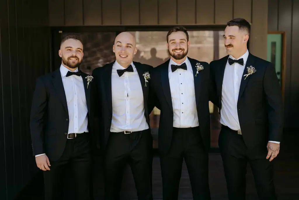 Groom and groomsmen standing together in their wedding suits