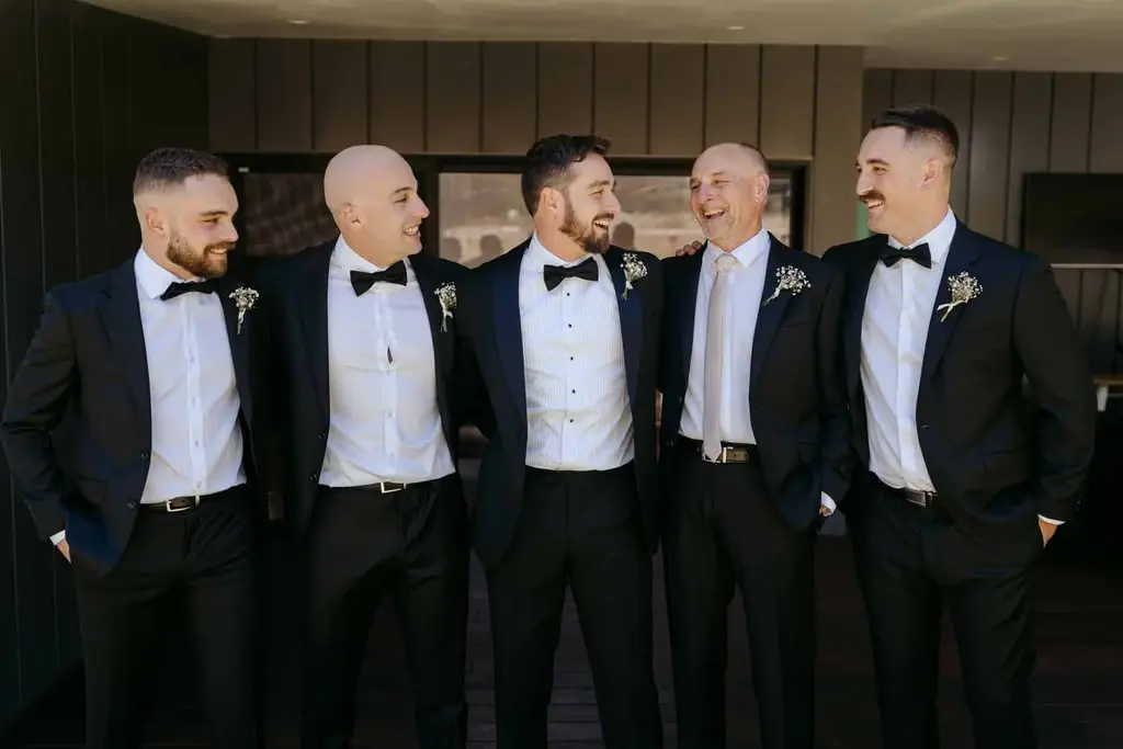 Groom and groomsmen laughing together outside