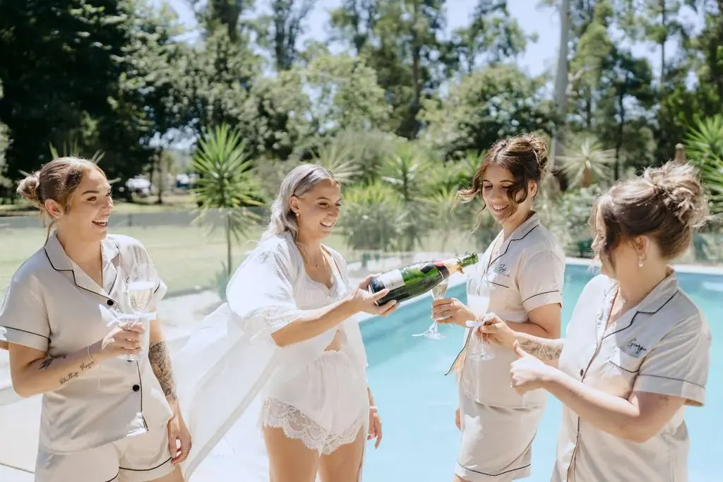 Bride and attendants talking beside a swimming pool