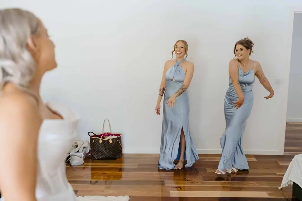 Bride watching two bridesmaids in pale blue dresses