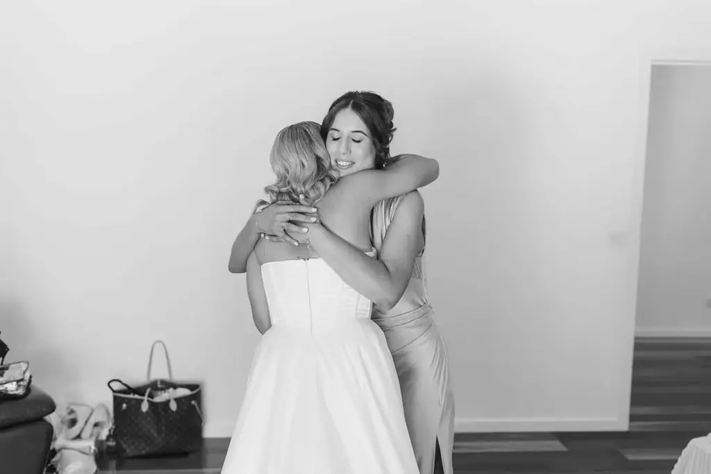 Black-and-white photograph of the bride embracing a guest