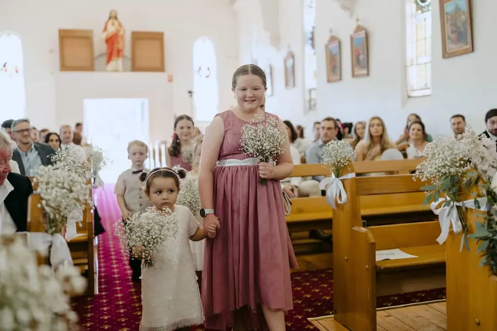 Bridesmaids and a flower girl walking down the church aisle