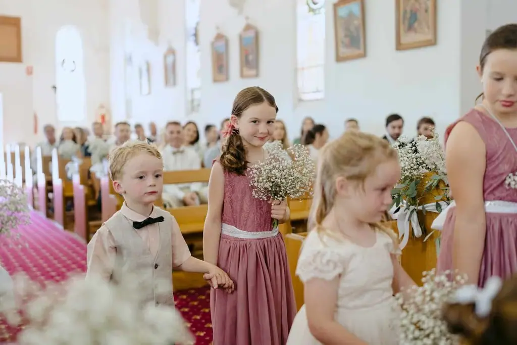 Children and bridesmaids walking down the church aisle