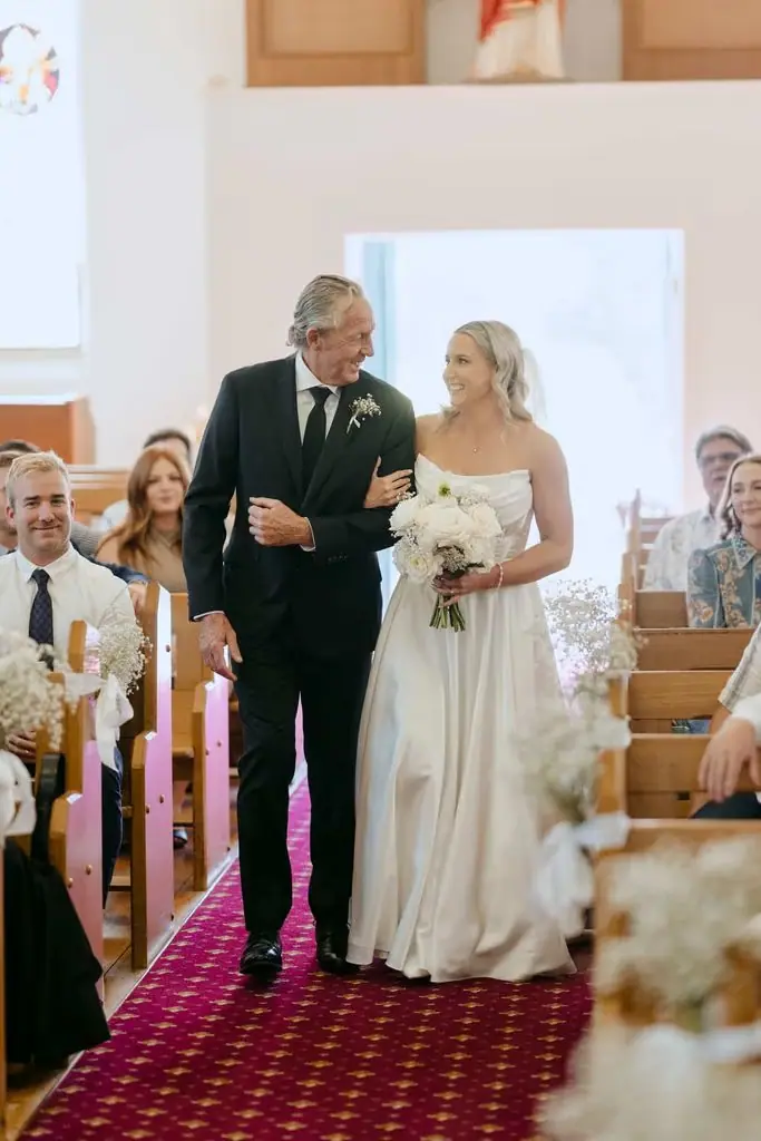 Bride walking down the church aisle with an older guest