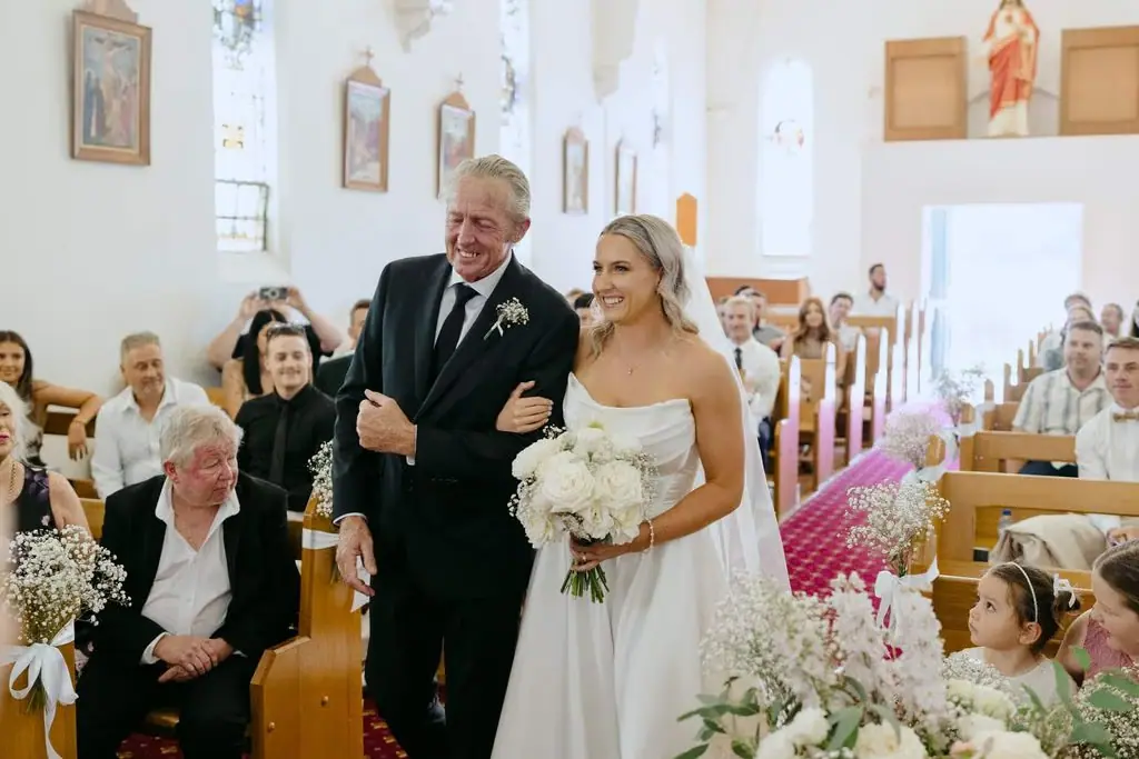 Bride smiling as she enters the church with an older guest