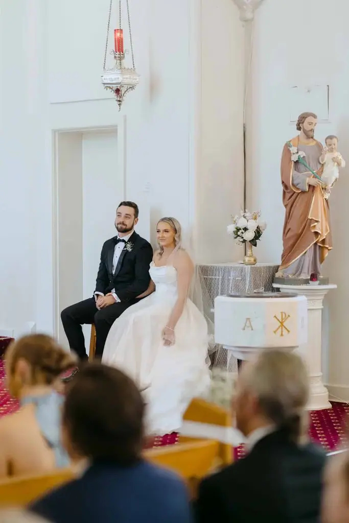Newlyweds seated beside each other at the front of the church