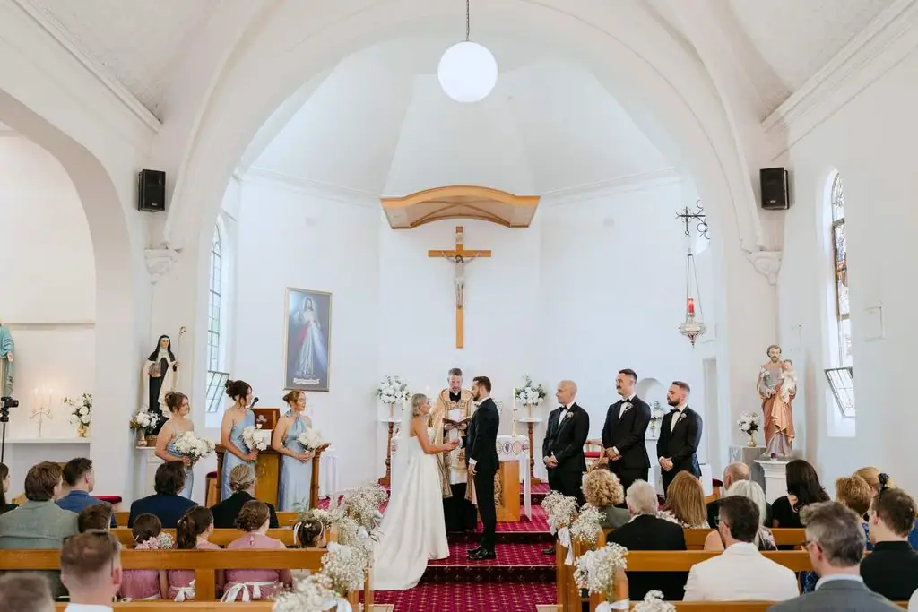 Couple standing with the wedding party during the church ceremony