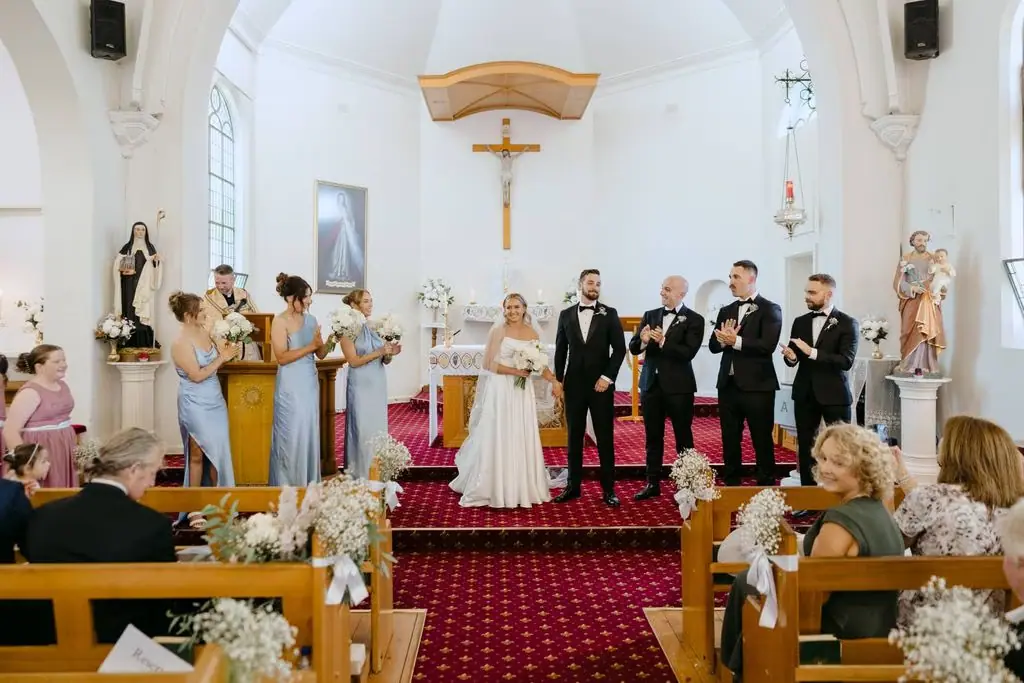 Wedding party standing before the priest inside the church