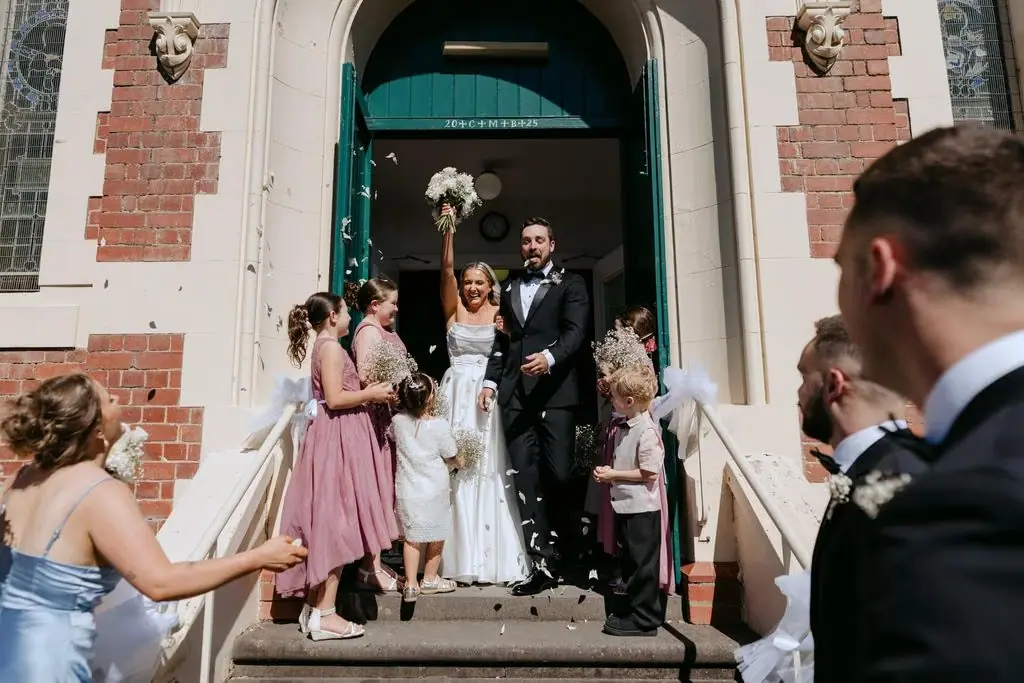 Newlyweds emerging from the church as guests throw confetti