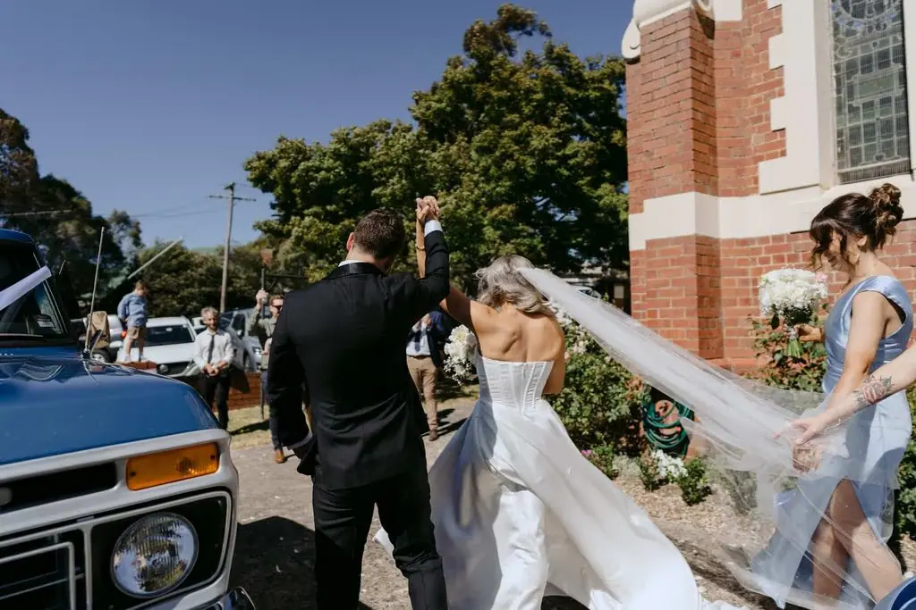 Bride approaching a blue pickup truck outside the church