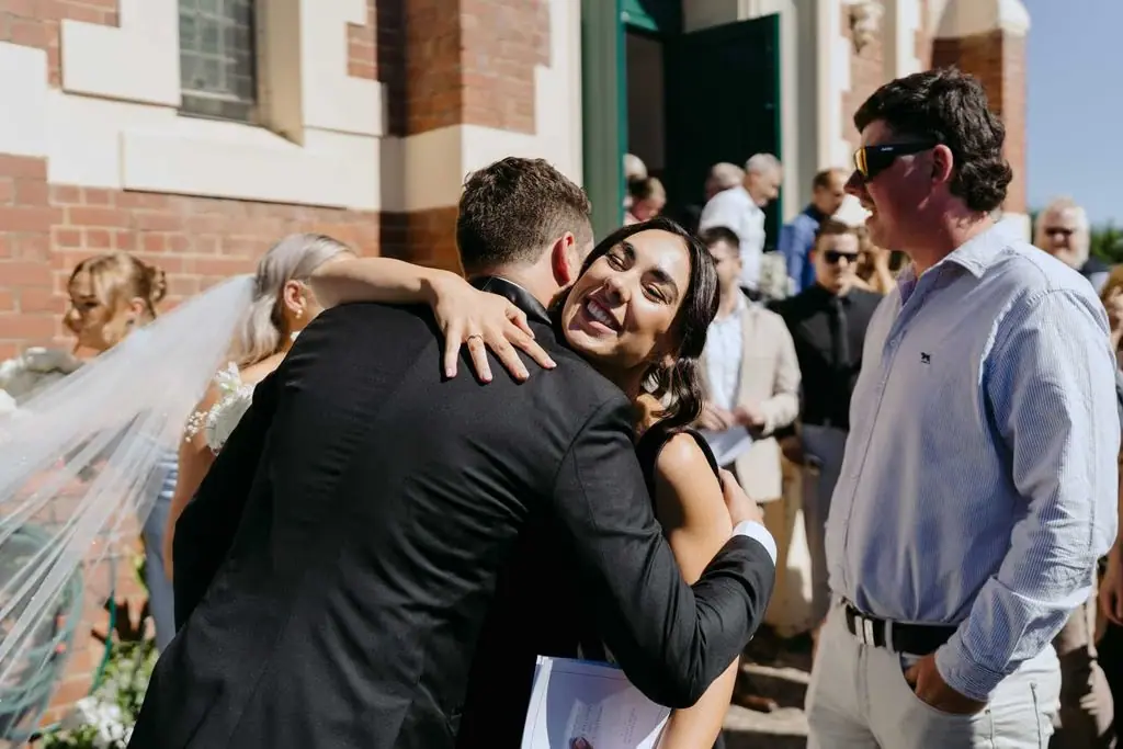 Groom embracing a guest outside the church entrance