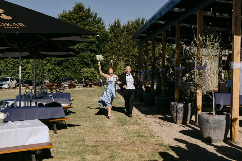 Groom walking towards the outdoor reception while raising a glass