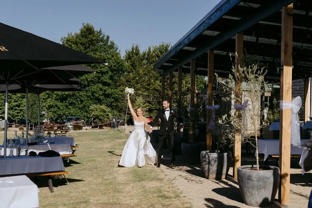 Bride raising her arm as she enters the outdoor reception
