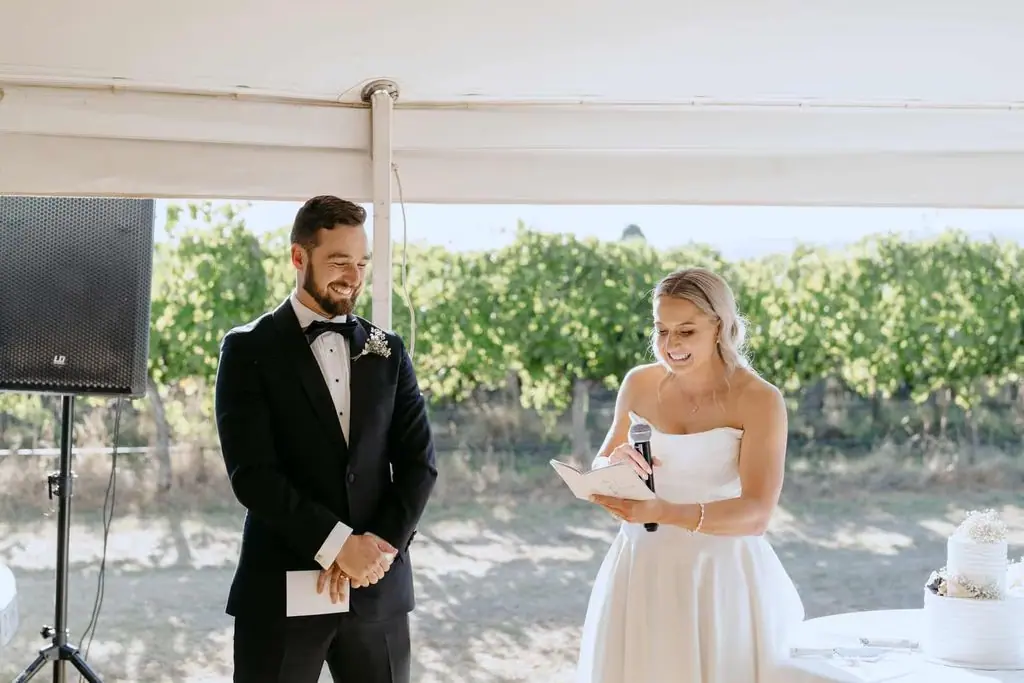 Bride speaking into a microphone beside the groom