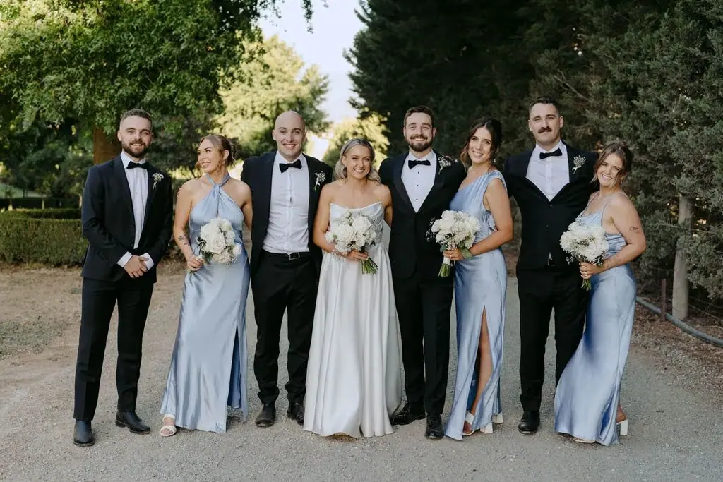 Wedding party posing together beneath leafy trees