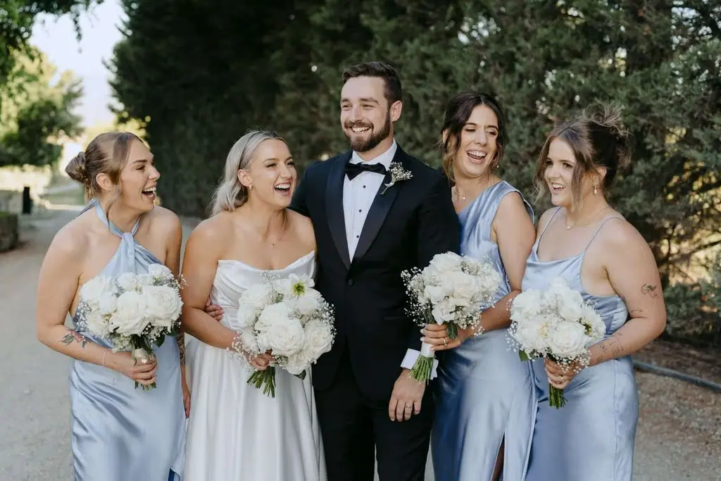 Bride, groom and three bridesmaids laughing together