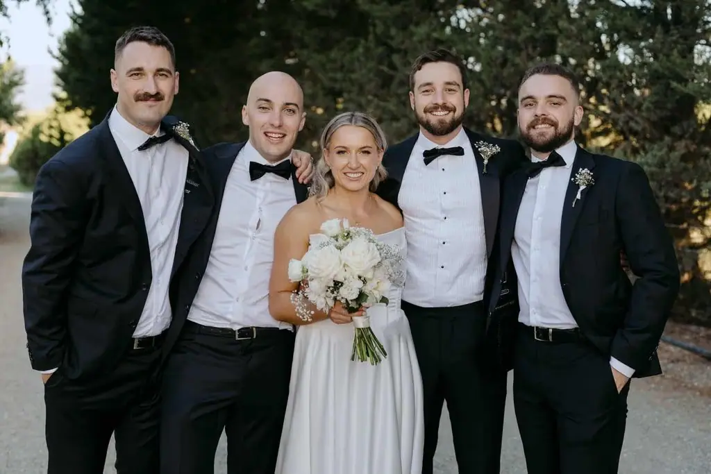 Bride posing with the groom and three groomsmen