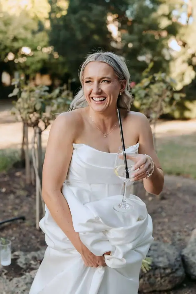 Bride smiling and holding up a glass in the garden