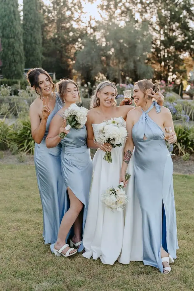 Bride and bridesmaids clinking glasses in evening light