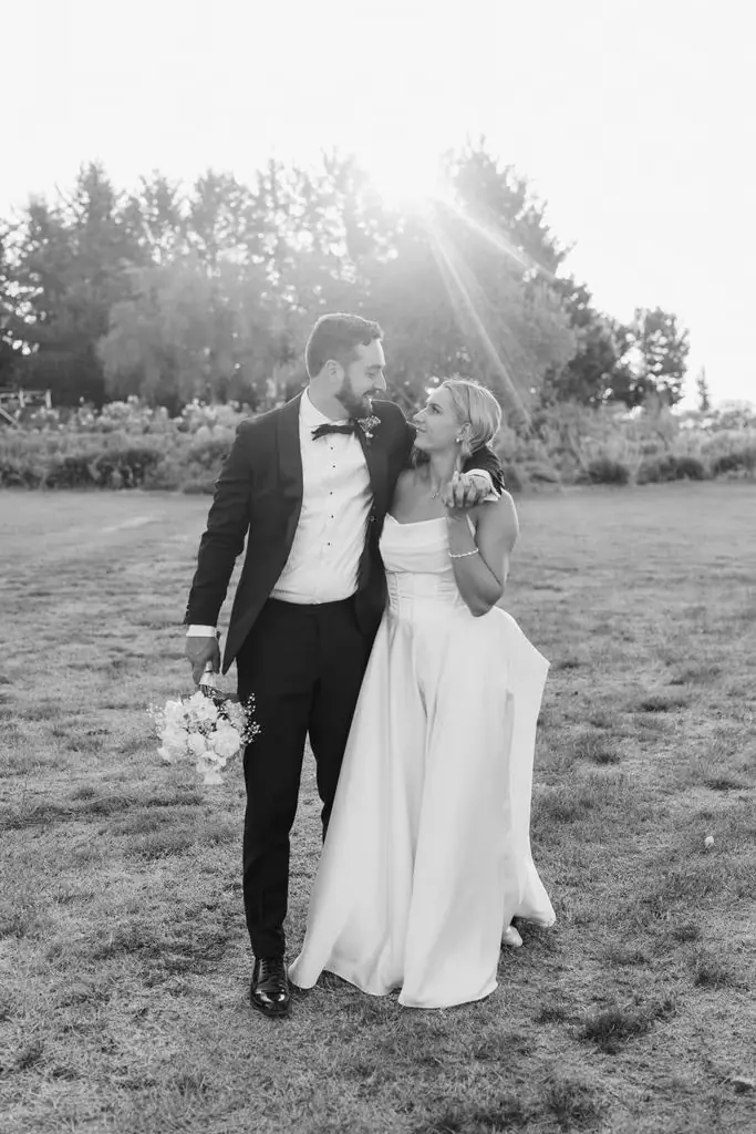 Black-and-white photograph of the couple walking together across a field