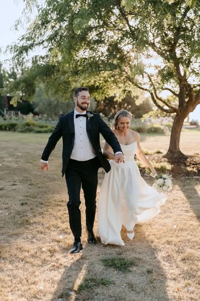Groom spreading his free arm as he walks beside the bride
