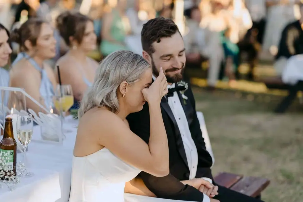 Bride laughing beside the groom during the reception speeches