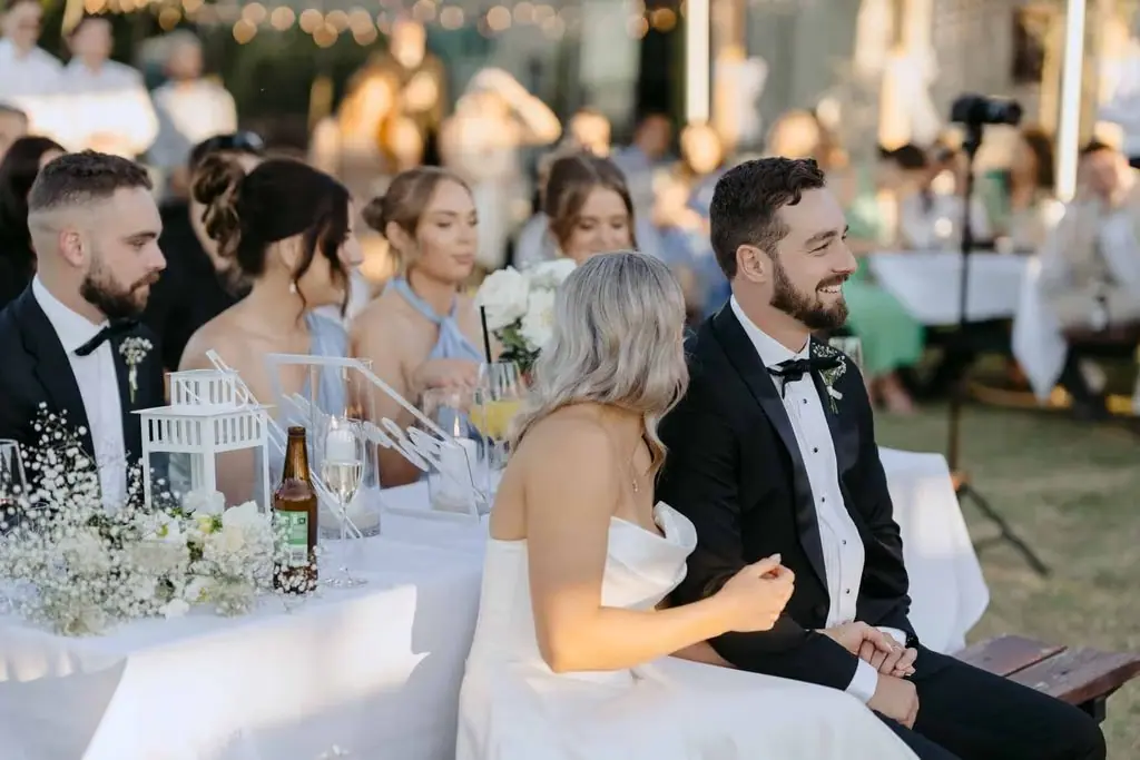 Newlyweds seated together and smiling at the reception