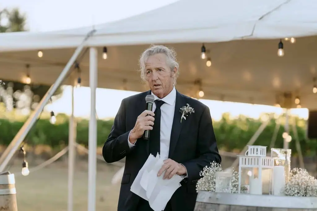 Older guest giving a speech beneath the marquee